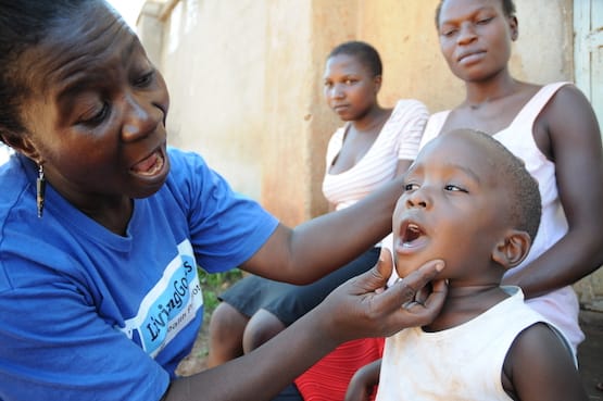 Living Goods community health worker looking in little boy's mouth